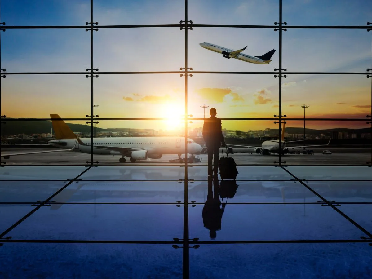 Traveller at an airport window at sunset